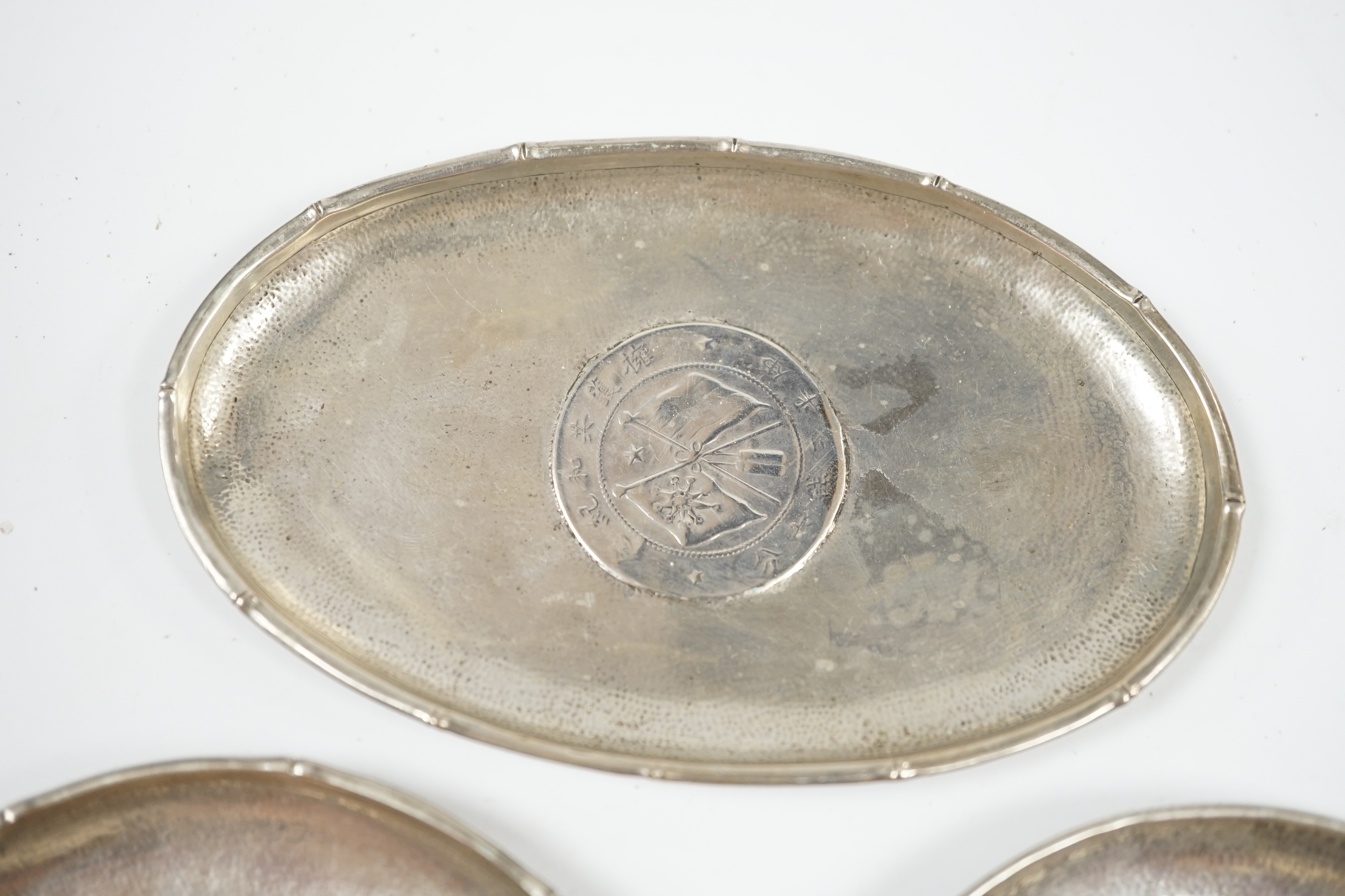 Three assorted small Chinese white metal dish, each inset with a coin, largest 11.8cm. Condition - fair